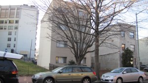 The building on the left would be displaced by new townhomes, which would also encompass the empty lots on both sides.  The building on the right would remain.