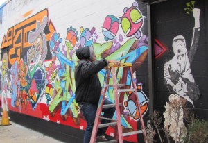 Juan Pineda, one of the graffiti artists participating in the Hello my name is show works on a piece on The Fridge exterior