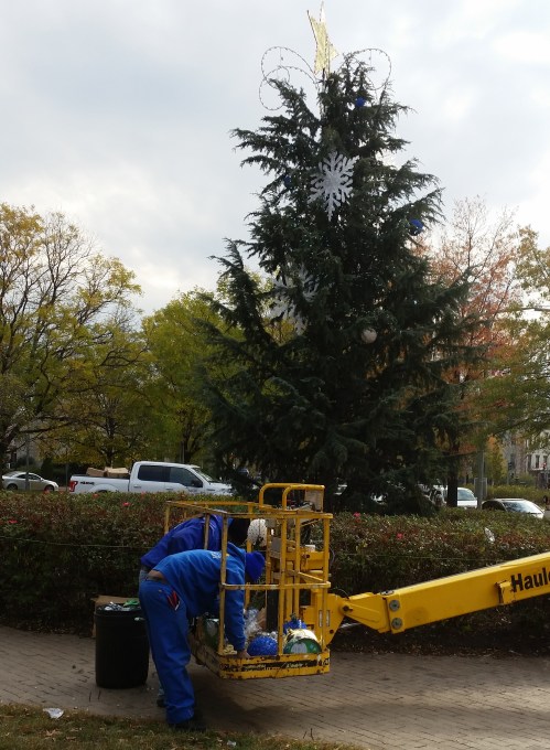 Capitol Hll BID began decorating the Eastern Market Metro Holiday tree in the large circle garden at Eastern Market Metro Plaza’s Northeast quadrant.  The tree honors BID’s founding President, George Didden, III.  