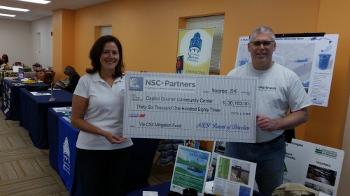 Bruce DarConte and Emily Franc with a check for $36183 for purchasing equipment presented to the Community Center on Saturday.  The funding comes from the benefits and amenities package the community received from CSX as compensation for the impact of reconstruction of the CSX tunnel.  DarConte is Founder and President of Near Southeast Community Partners, http://www.nscpartners.org/  a 501c3 nonprofit – which is the vehicle through which CSX Tunnel Community Benefits are distributed to the community.  Emily Franc heads up Anacostia Riverkeeper  http://bit.ly/2fhwkxp 